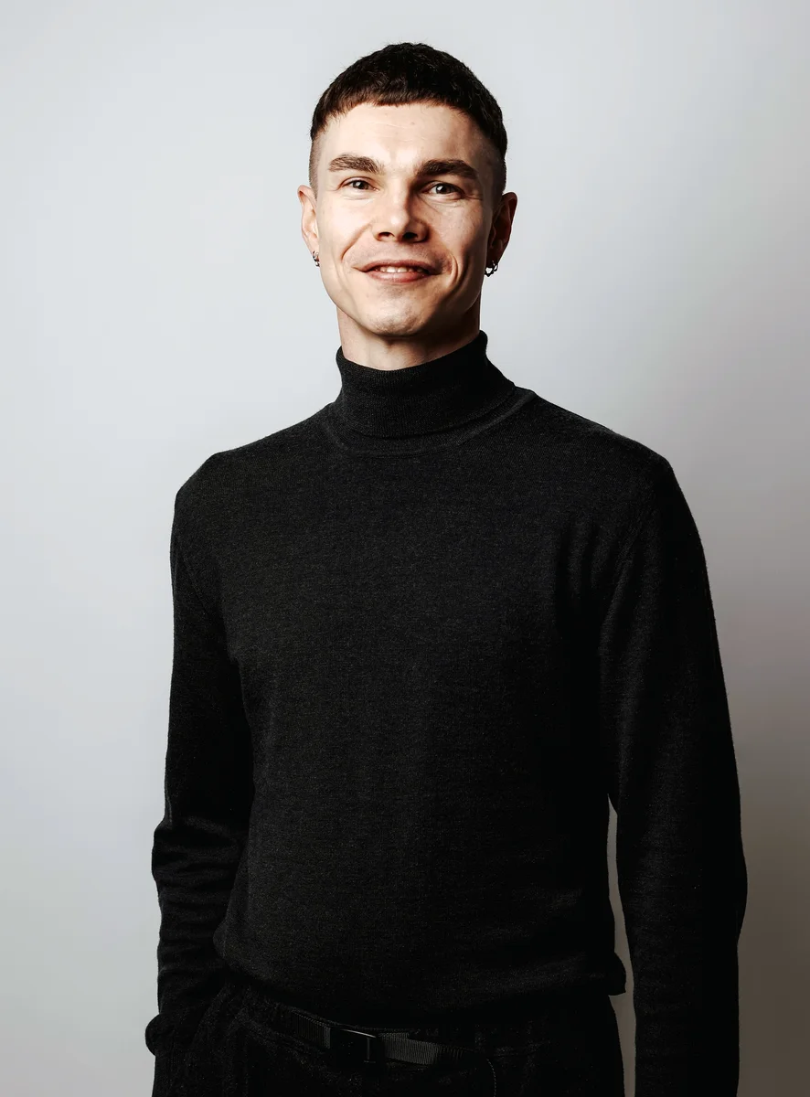 Ricki Walter smiling in a dark turtleneck, photographed in black and white.